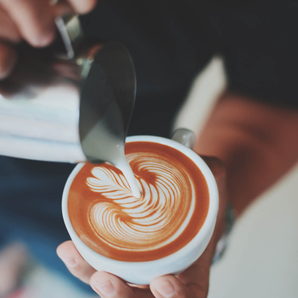 barista creating latte art on a perfect cup of coffee